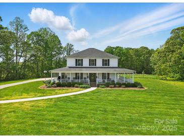 Charming two-story home featuring a wraparound porch and manicured lawn at 725 Bradshaw Rd, Mt Ulla, NC 28125