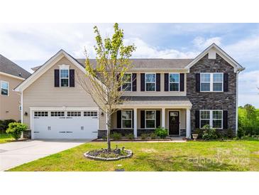 Two story home features a blend of vinyl siding and stone facade with neat landscaping at 7412 Greene Mill Sw Ave, Concord, NC 28025