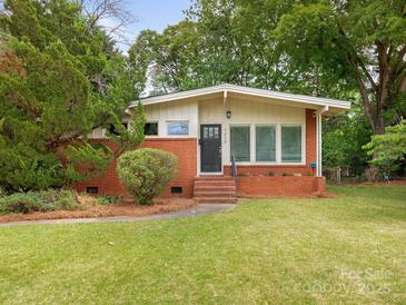 Charming brick home with lush green lawn, mature trees, and inviting front entrance at 1438 Larkfield Ln, Charlotte, NC 28210