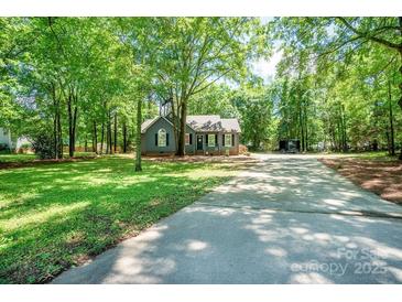 Charming single-story home with mature trees, a manicured lawn, and a long driveway at 1522 Stafford Ext, Monroe, NC 28110