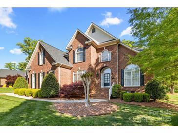 A corner view of a brick two-story home featuring black shutters and manicured landscaping at 204 Limerick Dr, Matthews, NC 28104