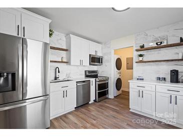 Bright kitchen features stainless steel appliances, floating shelves, and sleek white cabinetry at 232 Avery St, Fort Mill, SC 29715