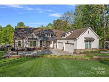 Beautiful white farmhouse exterior with a three-car garage and well-manicured lawn on a sunny day at 327 Kenway Loop, Mooresville, NC 28117