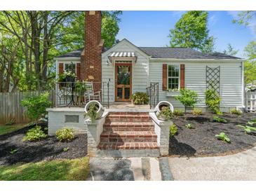 Charming home featuring a brick chimney, black and white awning, brick steps, and mature landscaping at 56 Blume Sw Ave, Concord, NC 28025