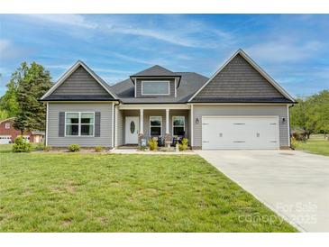 Charming one-story home boasts a manicured lawn, inviting front porch, attached two-car garage, and neutral siding at 604 Airport Rd, Kannapolis, NC 28081