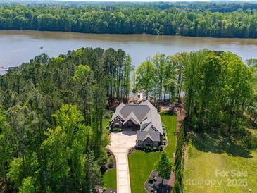 Stunning aerial view of a luxury waterfront home with lush landscaping and private dock at 1579 Sunset Pointe Dr, Salisbury, NC 28146