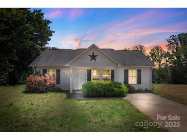 Charming single-story home with well-maintained lawn and landscaping, including flowering shrubs, under a colorful dusk sky at 244 Whitesides Rd, Bessemer City, NC 28016