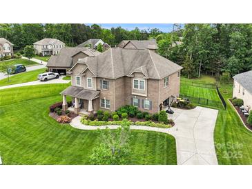 Beautiful brick home with manicured lawn and landscaping, featuring a long driveway and mature trees at 2655 Stonewood Vw, Kannapolis, NC 28081