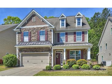 Charming two-story home featuring a stone facade, dormer windows, a two-car garage, and beautifully landscaped front yard at 79115 Ridgehaven Rd, Lancaster, SC 29720