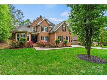 Inviting two-story brick home featuring a lush lawn and manicured landscaping at 8032 Turnberry Ln, Stanley, NC 28164
