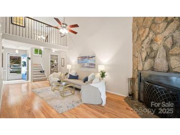 Bright living room with stone fireplace, neutral decor, and hardwood floors in modern home at 8326 Ramath Dr, Charlotte, NC 28211
