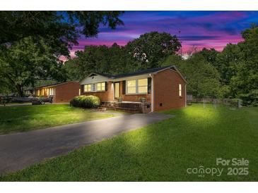 Beautiful brick home with manicured lawn at dusk, featuring inviting exterior lighting and a serene ambiance at 1053 Stoneybrook Ln, Rock Hill, SC 29730