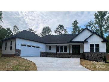 Charming single-story home featuring a 2-car garage, black roof and brick accents, with a pristine white exterior at 3723 Whitney Ne Dr, Hickory, NC 28601