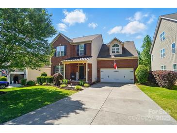 Charming two-story brick home with a well-manicured lawn and a two-car garage on a sunny day at 8004 Fountainbrook Dr # 15, Indian Trail, NC 28079
