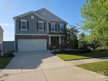 Charming two-story home with a stone facade, attached garage, and a well-maintained lawn on a sunny day at 106 Calderdale Ln, Charlotte, NC 28262