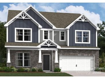 Charming two-story home featuring stone accents, blue siding, gabled roof, and an attached two-car garage at 1215 Fremont Dr, Wingate, NC 28174