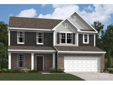 Charming two-story home featuring brick accents, a two-car garage, and professionally landscaped front yard at 1223 Fremont Dr, Wingate, NC 28174