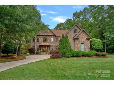 Stunning stone and brick home with a manicured lawn and lush landscaping, exuding curb appeal at 1305 Anniston Pl, Wesley Chapel, NC 28079