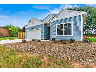 Charming home featuring a blue exterior, white trim, an attached garage, and a well-maintained front yard at 3567 Farmfield Dr, Claremont, NC 28610