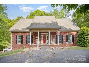 Charming brick home featuring a cozy front porch with rocking chairs and a red front door at 8300 Loma Linda Ln, Waxhaw, NC 28173