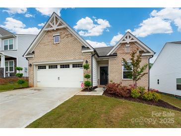 Charming brick home with a well-manicured lawn and a two-car garage with an inviting entrance and beautiful landscaping at 1024 Scotch Meadows Loop # 32, Monroe, NC 28110
