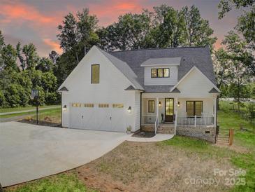 Stunning two-story home featuring a manicured lawn, welcoming front porch, and attached two-car garage at 1030 Little Cowgirl Ln, Cleveland, NC 27013