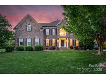 Charming two-story brick home featuring a manicured lawn and inviting entrance with white columns at 1116 Crooked River Dr, Waxhaw, NC 28173