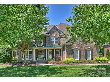 Traditional two-story brick home with a welcoming front porch and well-manicured landscaping at 16430 New Providence Ln, Charlotte, NC 28277