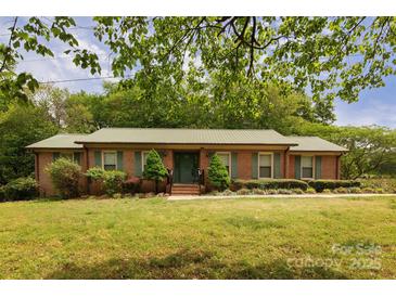 Charming brick ranch-style home with a metal roof, green shutters, and a well-maintained front yard at 3012 Morgan Mill Rd, Monroe, NC 28110