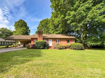 Charming single-story brick home featuring a covered carport, colorful flowers, and a well-maintained lawn at 437 Old Mountain Rd, Statesville, NC 28677