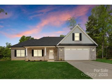 Charming single-story brick home with a well-manicured lawn and attached two-car garage at 5209 Carden Dr, Charlotte, NC 28227