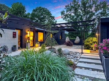 Beautifully landscaped front yard with lush greenery, stone accents, and a modern pergola at twilight at 6508 Trenton Pl, Charlotte, NC 28226