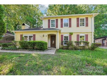 Charming two-story home with yellow siding, red shutters, and a brick entryway at 6807 Woodfield Dr, Charlotte, NC 28215