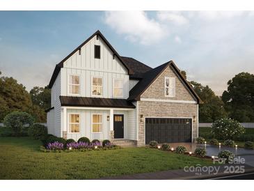 Charming two-story home with light siding, stone accents, a dark roof, and a manicured front lawn and garden at Lot 4 Rocky River Crossing Rd, Harrisburg, NC 28075