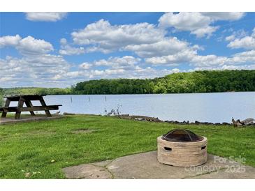 Scenic backyard featuring a picnic table, fire pit, and picturesque lake views for outdoor enjoyment at 1404 River Dr, Belmont, NC 28012