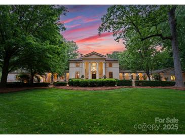 Stately home with manicured lawn, mature trees, and impressive architectural details at sunset at 5030 Hardison Rd, Charlotte, NC 28226