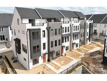 Modern townhome complex with white and gray exteriors, balconies, and well-defined landscaping at 6009 Countess Dr # 50, Charlotte, NC 28217