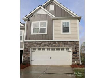Stylish two-story home with a white garage door, stone accents, and mixed gray and beige siding at 3217 Lilac Grove Dr, Charlotte, NC 28269