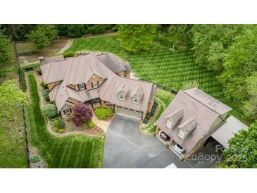 Sprawling estate with manicured lawn, featuring a brick home and detached garage, surrounded by mature trees at 4600 Spicewood Dr, Charlotte, NC 28227