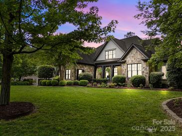 Beautiful stone home with a well-manicured lawn and lush landscaping showcasing its curb appeal at 21305 Sandy Cove Rd, Cornelius, NC 28031