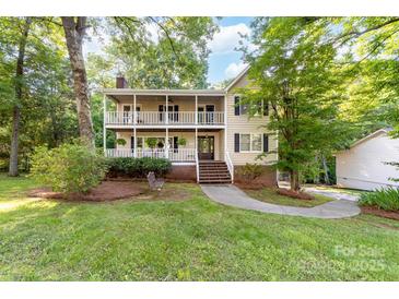 Charming two-story home featuring a double porch and inviting curb appeal surrounded by mature trees at 552 Blue Rock Dr, Charlotte, NC 28213