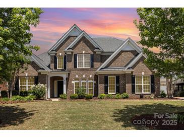 Beautiful two-story brick home with a manicured lawn, black shutters, and mature trees enhancing its curb appeal at 10202 Alouette Dr, Waxhaw, NC 28173