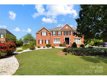Beautiful red brick home with manicured front yard and landscaping on a bright day at 11917 Chevis Ct, Charlotte, NC 28277