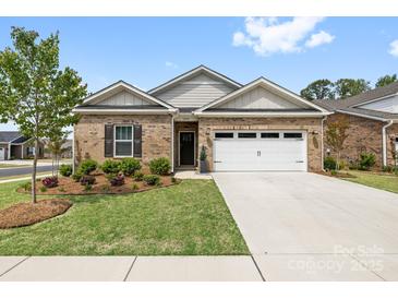 Inviting brick home featuring a well-manicured lawn, an attached two-car garage, and lovely landscaping at 12705 Twilight Dr, Mint Hill, NC 28227