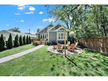 Inviting backyard features a fire pit with chairs, a lush lawn, and a charming gray home exterior at 1517 Parkwood Ave, Charlotte, NC 28205