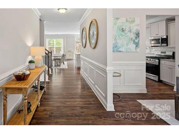 Bright foyer with hardwood floors, decorative mirrors and wainscoting, leading into the open-concept kitchen and living area at 2032 Burton Point Ct, Waxhaw, NC 28173
