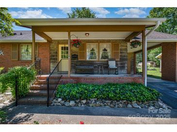 Charming brick home featuring a cozy covered front porch with inviting seating and hanging flower baskets at 3624 Delgany Dr, Charlotte, NC 28215
