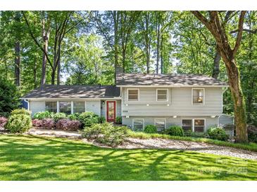Charming two-story home with grey siding, red door, beautiful landscaping, and mature trees at 3329 Winnipeg Cir, Charlotte, NC 28210