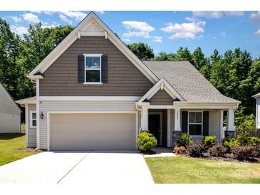 Charming home featuring a two-car garage, manicured lawn, and inviting front porch at 5053 Arbordale Way, Mount Holly, NC 28120