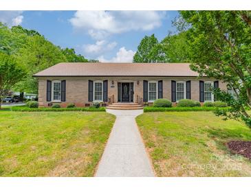 Charming brick home with a lush green lawn and manicured landscaping in front at 5522 Sharon Rd, Charlotte, NC 28210